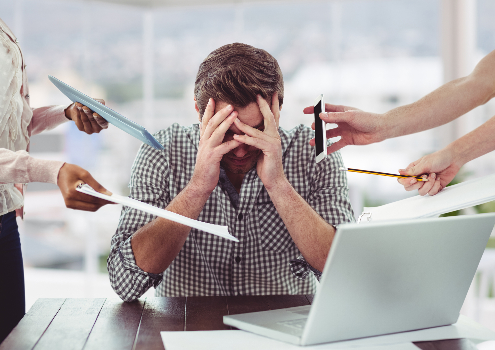 Gestresster Büroangestellter, der von mehreren Seiten mit Aufgaben überhäuft wird. Symbolbild für ineffiziente Prozesse und Lean Administration.